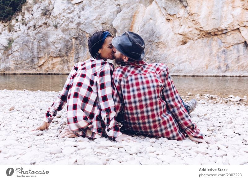 Positive woman and man resting and kissing on stone shore near river Couple Mountain River Stone Rock Smiling Woman Man Coast Lie (Untruth) Attractive Hill