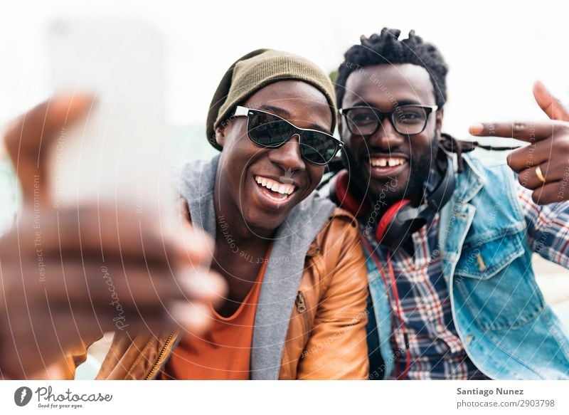 Two black race friends having fun. Friendship Telephone Cellphone Town African Black American Mobile Youth (Young adults) Man Laughter PDA Technology