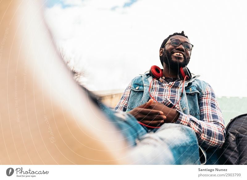 African Young Man Listening Music. Headphones Lifestyle Black American Town Portrait photograph Telephone PDA Mobile Solar cell handsome Technology Stand