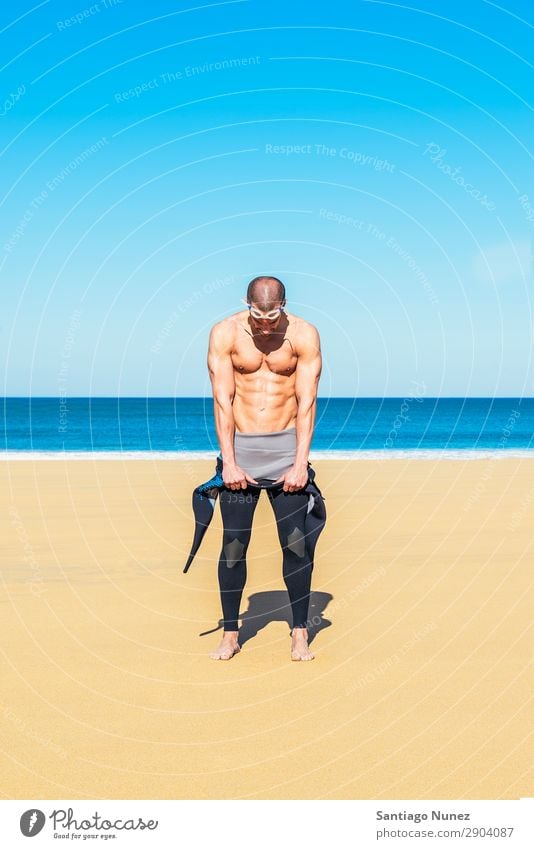 swimmer putting on his wetsuit on the beach - a Royalty Free Stock Photo  from Photocase