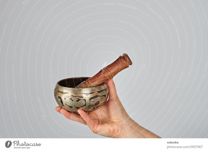 copper singing bowl and wooden stick in female hand Bowl Lifestyle Body Relaxation Meditation Music Yoga Woman Adults Hand Metal White Peace Religion and faith