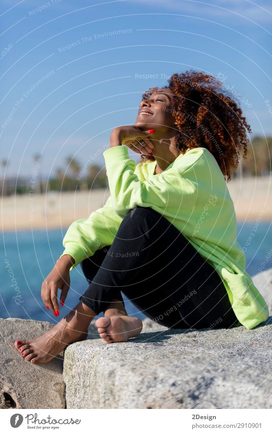 Side view of beautiful curly afro woman sitting on breakwater Lifestyle Style Beautiful Hair and hairstyles Face Ocean Human being Feminine Young woman