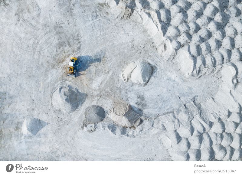A yellow wheel loader stands between piles of stones in a gravel pit Aerial Air Bavaria Bird's Eye View Construction Drone Germany Grey Landscape Machine Mine