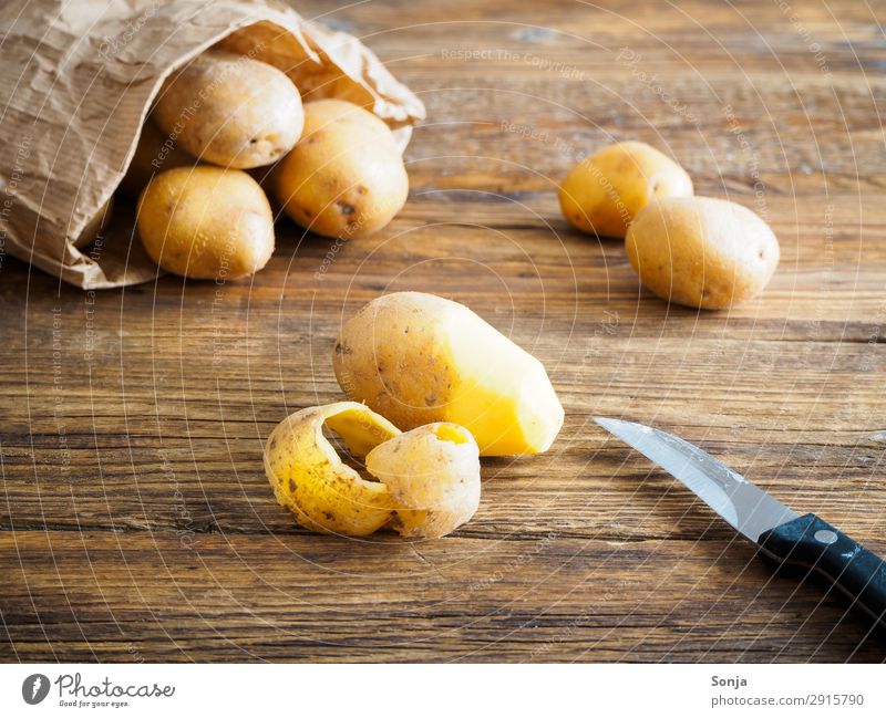 Potatoes in a paper bag Food Vegetable Nutrition Organic produce Vegetarian diet Knives Healthy Eating Brown wooden table Good Delicious To enjoy Colour photo