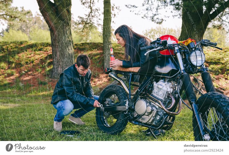 Man fixing his motorcycle while his girlfriend looks at him Drinking Cold drink Alcoholic drinks Beer Lifestyle Vacation & Travel Trip To talk Human being Woman