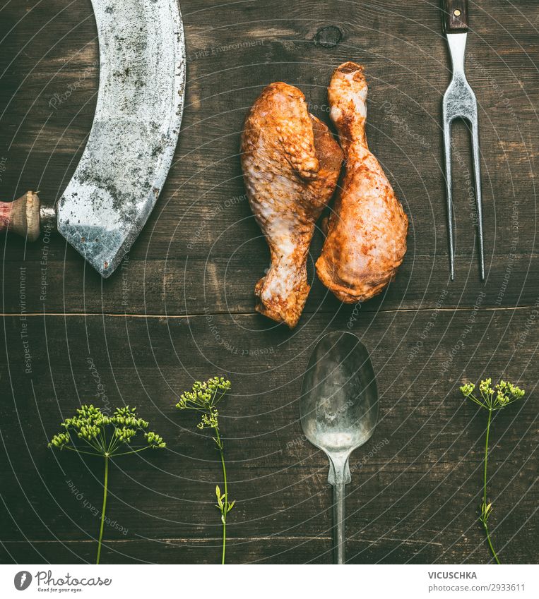 Raw barbecue marinated chicken drumstick with fresh herbs and kitchen utensils on rustic wooden background, top view. Grill preparation raw grill steakhouse