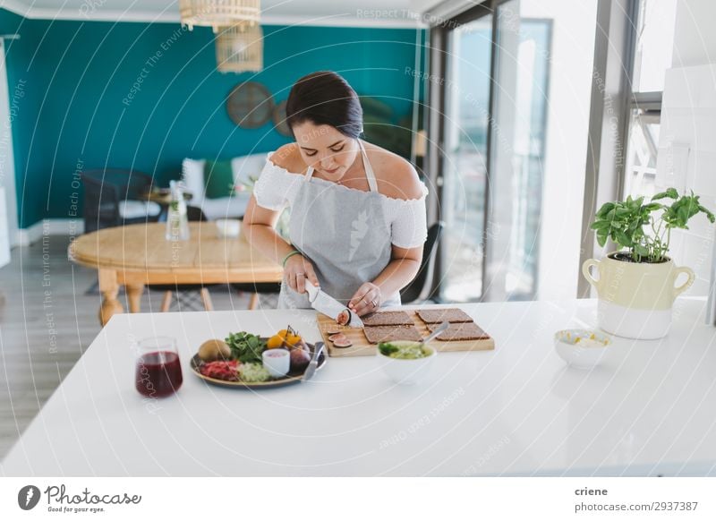 Woman preparing sandwiches in kitchen Vegetable Bread Kitchen Adults Smiling food healthy indoor Home cooking chef Ingredients Tomato knife cutting toast