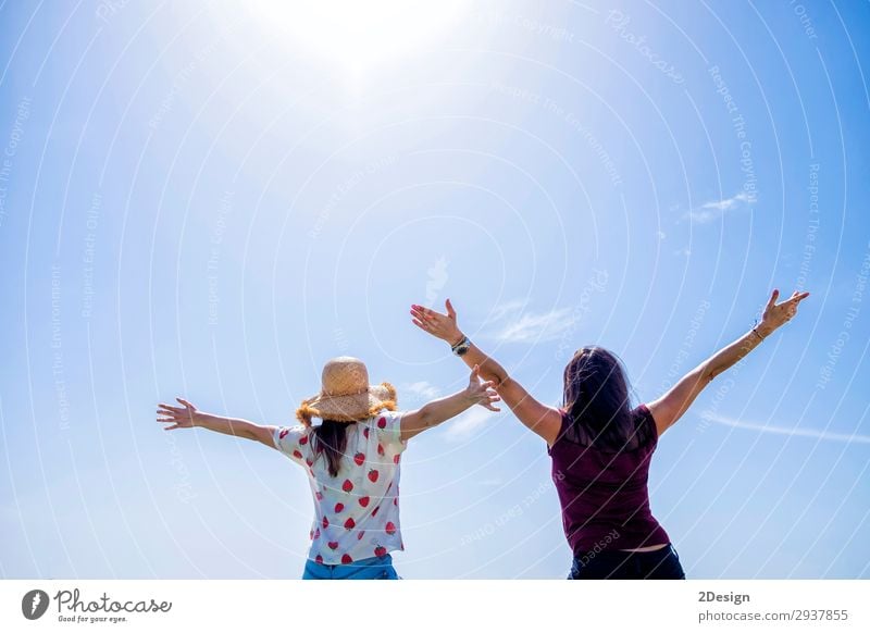 Two young woman sitting on a fence arms raised against blue sky Lifestyle Joy Happy Beautiful Relaxation Leisure and hobbies Vacation & Travel Freedom Summer