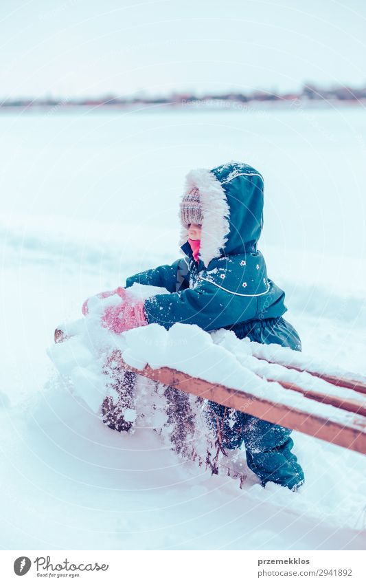 Little girl enjoying winter removing snow from a bench Lifestyle Joy Happy Playing Winter Snow Child Human being Woman Adults Infancy 1 Nature Landscape