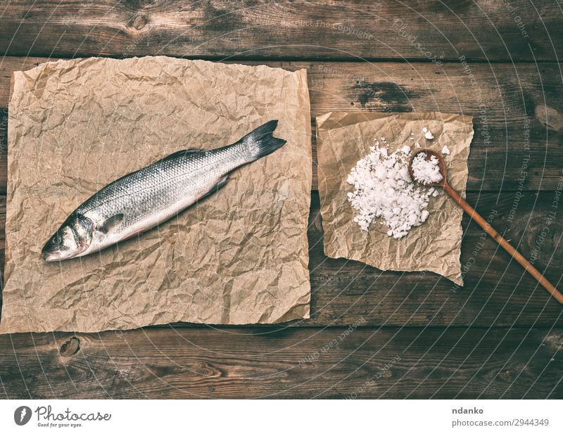 sea bass fish on brown crumpled paper Fish Seafood Nutrition Spoon Ocean Kitchen Animal Paper Wood Fresh Above Brown Gray salt board cooking labrax one Raw