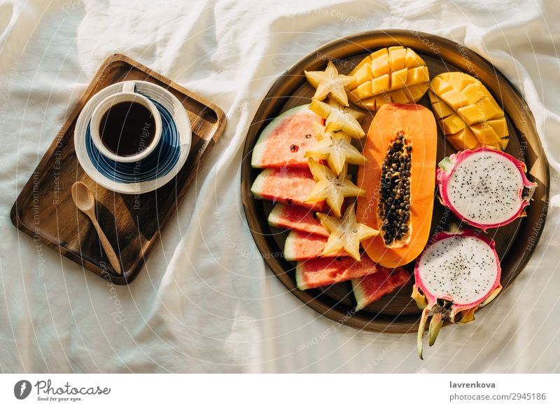 Coffee or tea and tropical fruit plat on white bed Bedroom Beverage Breakfast Carambole Cup Dragonfruit Exotic flatlay Healthy Eating Mango Morning Mug Notebook