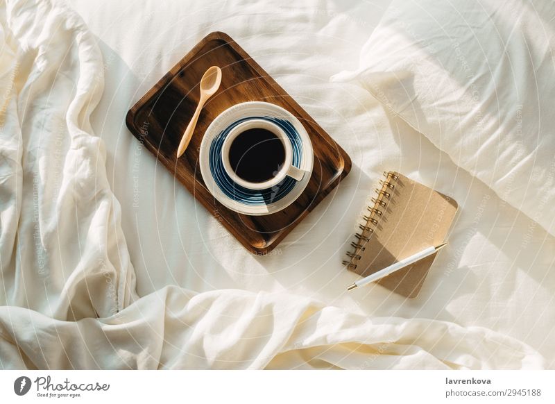 Coffee on wooden tray with notebook and pen on bed flatlay Tray Wood Spoon Tea Bedroom sheets Pillow Pen Hot Paper Notebook Cup Mug Vantage point Top Brown