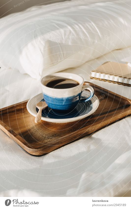 Coffee on wooden tray with notebook and pen on bed background Bedroom Beverage Breakfast Brown Cup Hot Morning Mug Notebook Paper Pen Pillow Sheet Spoon Table