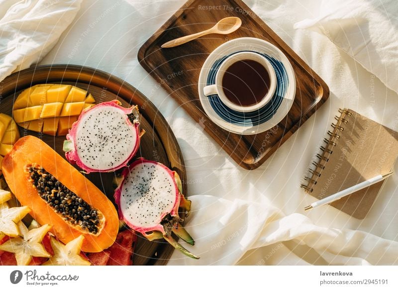 Coffee or tea on wooden tray and tropical fruit plate Tropical Exotic Carambole Mango pitahaya Dragonfruit Plate Healthy Eating plant based Vegan diet Papaya