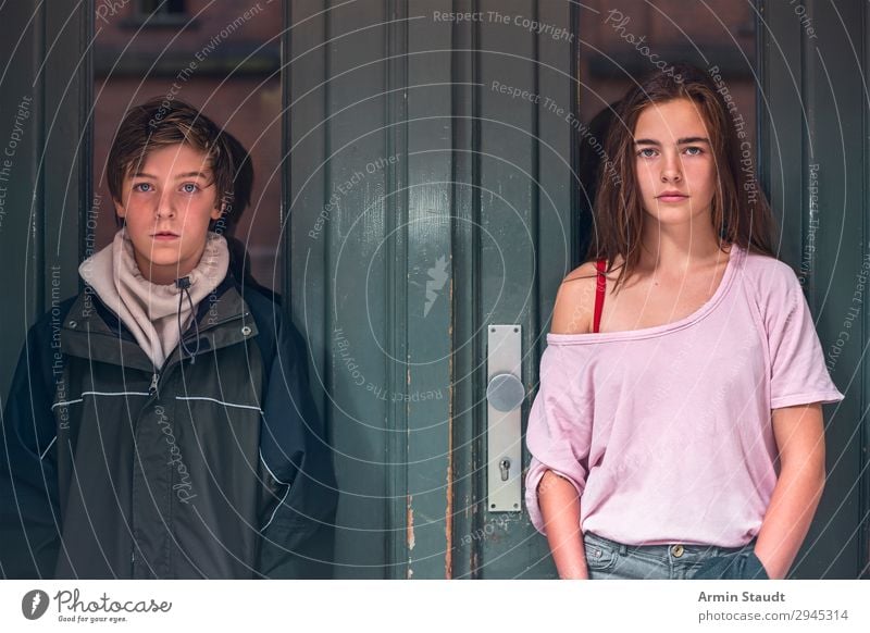 portrait of a boy and girl in front of a green door teen teenager teens two person confident street outdoor entrance casual young woman male caucasian female