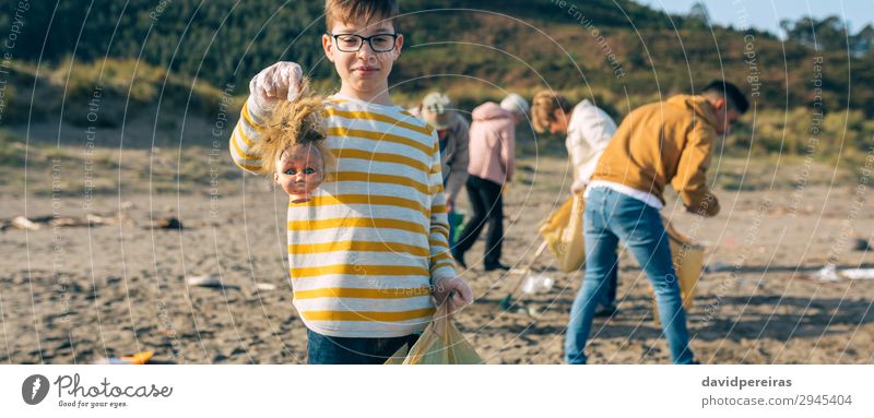 Boy showing doll head while cleaning the beach Beach Child Work and employment Internet Human being Boy (child) Woman Adults Man Family & Relations Group