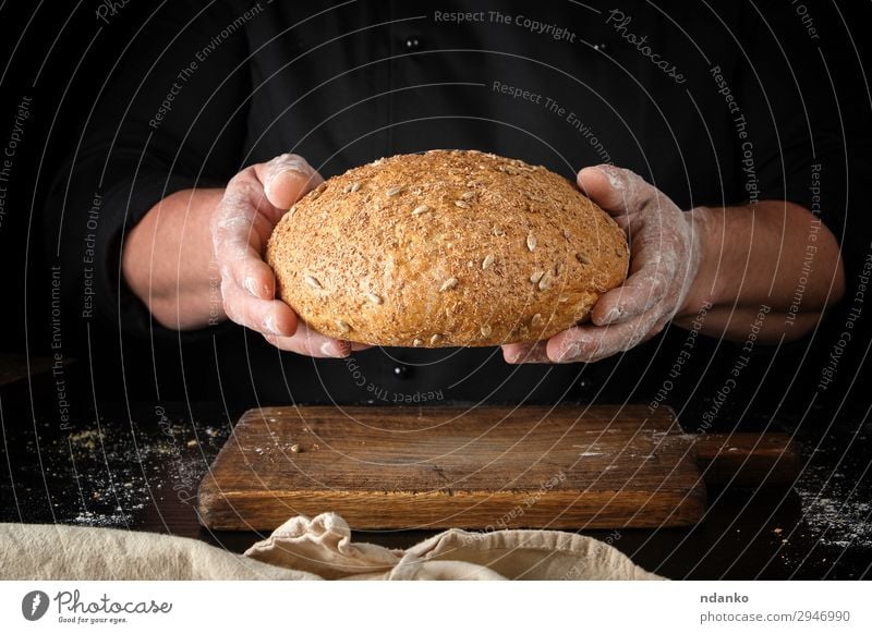male hands are holding brown baked rye bread Bread Nutrition Eating Lunch Dinner Diet Table Kitchen Man Adults Hand Wood To hold on Dark Fresh Delicious Natural
