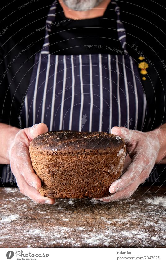 hands are holding brown baked rye bread Bread Nutrition Eating Lunch Dinner Diet Table Kitchen Man Adults Hand Wood Dark Fresh Delicious Natural Brown Black