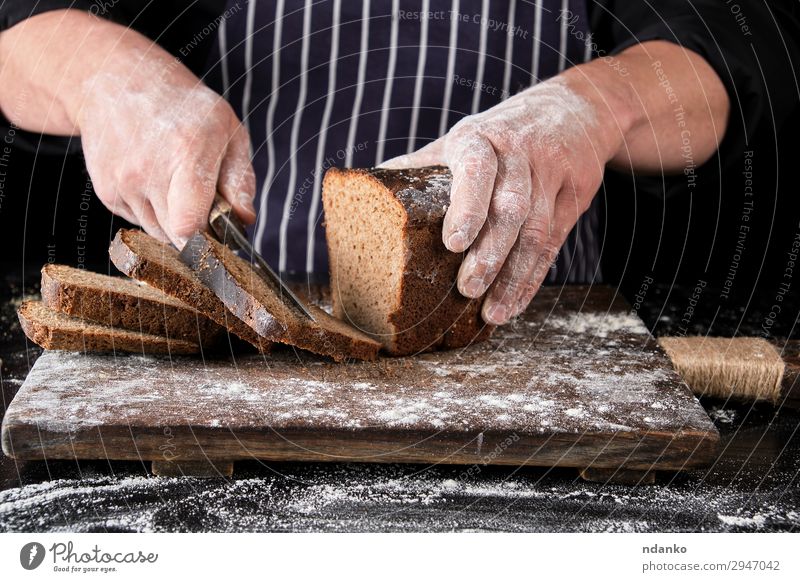 chef in black uniform holds a kitchen knife Bread Nutrition Eating Lunch Dinner Knives Table Kitchen Man Adults Hand Wood Dark Fresh Delicious Natural Brown