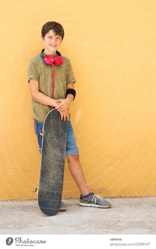 Young boy leaning on a yellow wall with headphones on neck Style Music Child Telephone PDA Human being Masculine Boy (child) Young man Youth (Young adults) Man