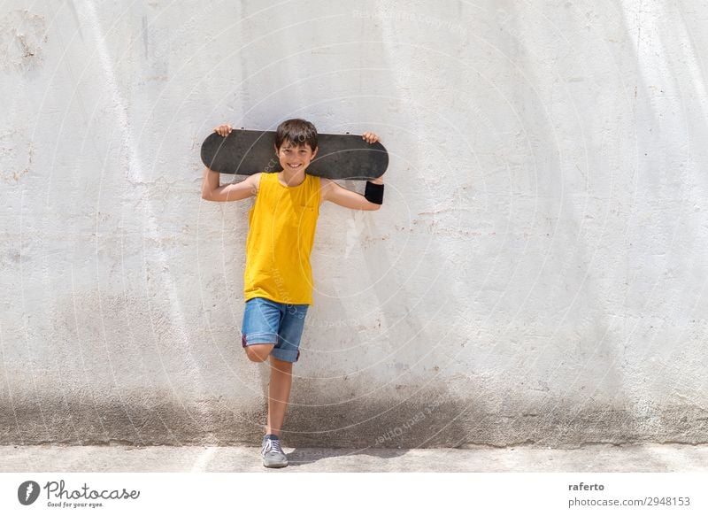 Young smiling boy leaning on yellow wall holding a skateboard Style Happy Child Human being Masculine Boy (child) Young man Youth (Young adults) 1