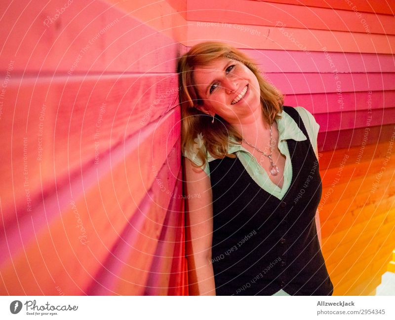 young woman leans happily against a colourful wooden wall Interior shot 1 Person Young woman Artificial light Portrait photograph Forward