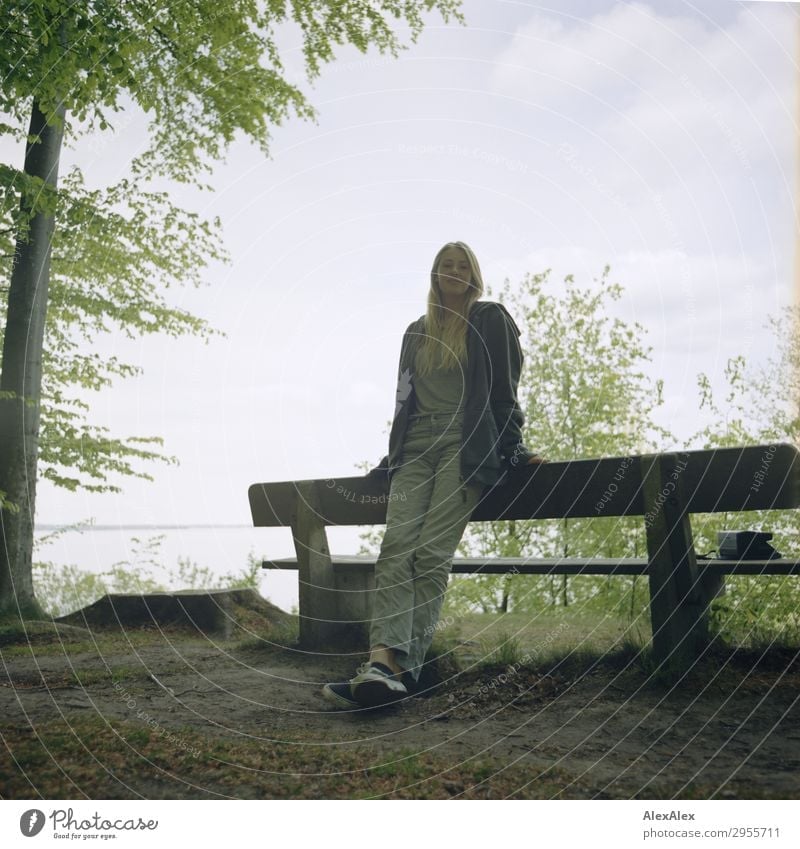 Young woman leaning on a park bench at the Baltic Sea in the forest Joy Beautiful Harmonious Well-being Youth (Young adults) 18 - 30 years Adults Nature