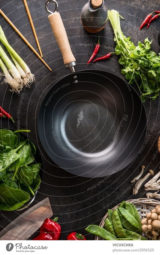 Empty wok pan on kitchen table with chopsticks and vegetarian Asian food ingredients, top view. Copy space.  Healthy eating and cooking empty asian food