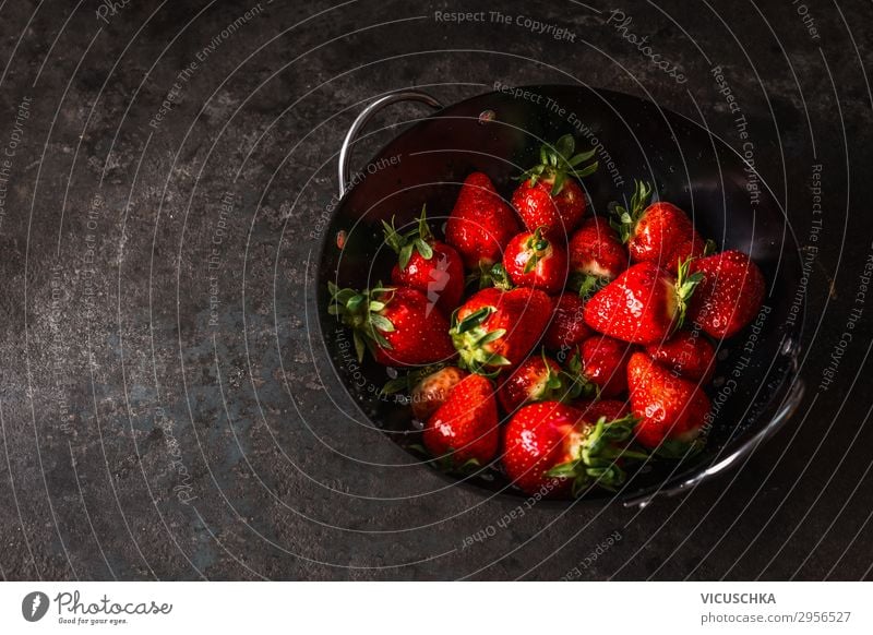 Tasty strawberries in black colander bowl on dark rustic kitchen table. Copy space. Seasonal organic food. Healthy eating and cooking tasty copy space seasonal