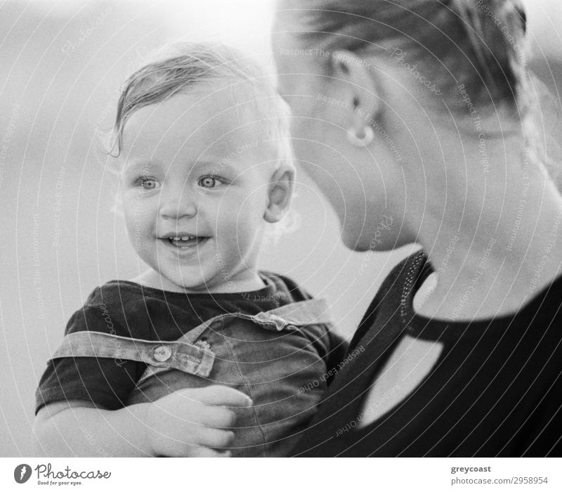 Black and white shot of young mother carrying and looking at joyful one year baby girl with love. Happy motherhood Style Joy Child Human being Baby Woman Adults