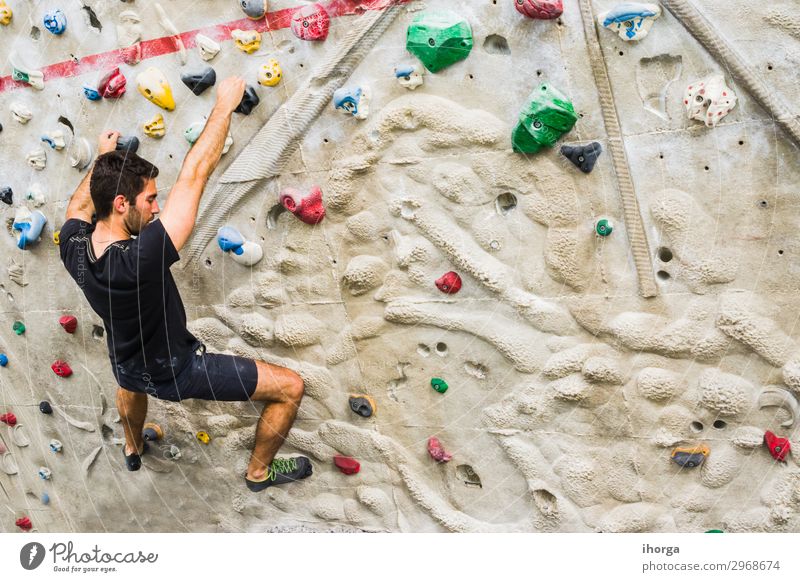 Man practicing rock climbing on artificial wall indoors. Active lifestyle and bouldering concept. active black chalk challenge clambering cliff climber