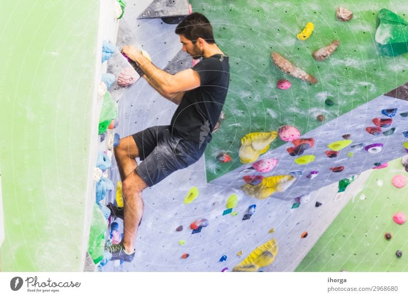 Man practicing rock climbing on artificial wall indoors. Lifestyle Joy Leisure and hobbies Sports Climbing Mountaineering Masculine Young man
