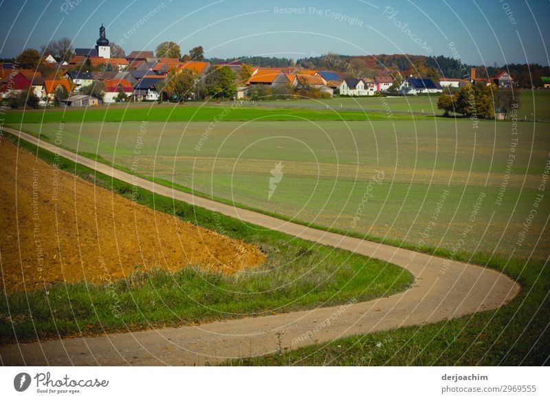 My way which curved through a meadow divided, to a small town in Franconia leads. In the background the village, houses and the church. Joy Life Harmonious