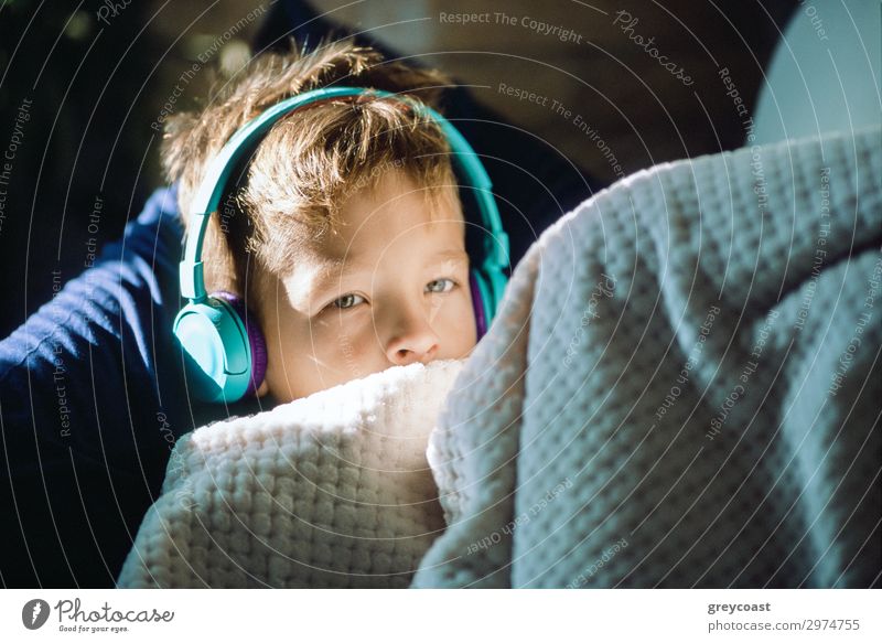 A close up of a boy in headphones, covered with a blanket Relaxation Music Headset Boy (child) Listening glance Headphones earpieces Rest leasure sunshine