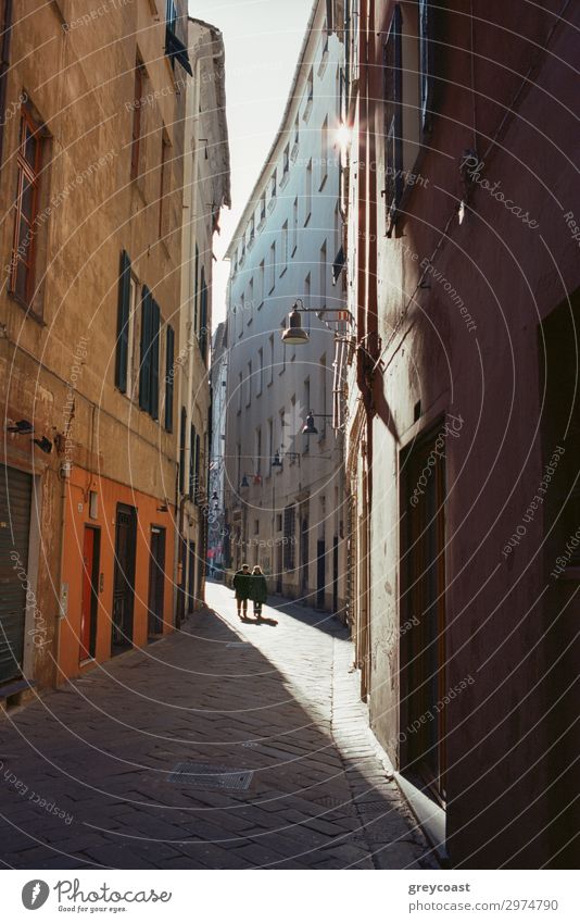 A narrow street between old italian buildings, with a thin sunlight corridor and two human figures far away Human being Town Building Pedestrian Street Historic