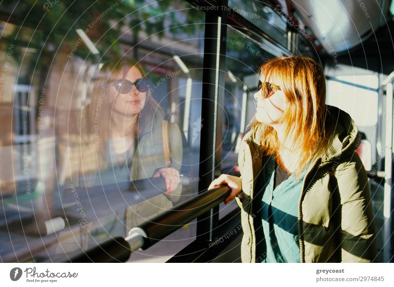 A young red-haired woman in sun glasses looking at her reflection in a bus window Vacation & Travel Trip City trip Human being Young woman Youth (Young adults)