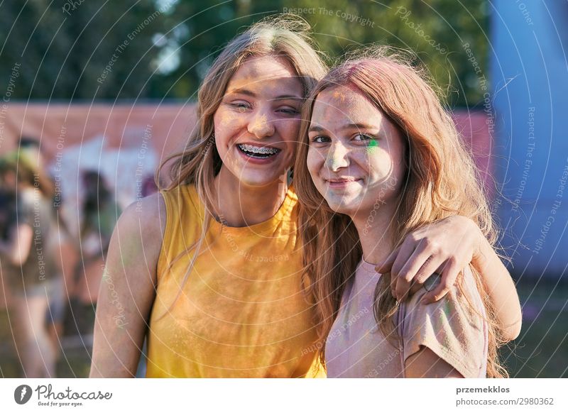 Portrait of happy smiling young girls with colorful paints on faces and clothes. Two friends spending time on holi color festival Lifestyle Style Joy Happy