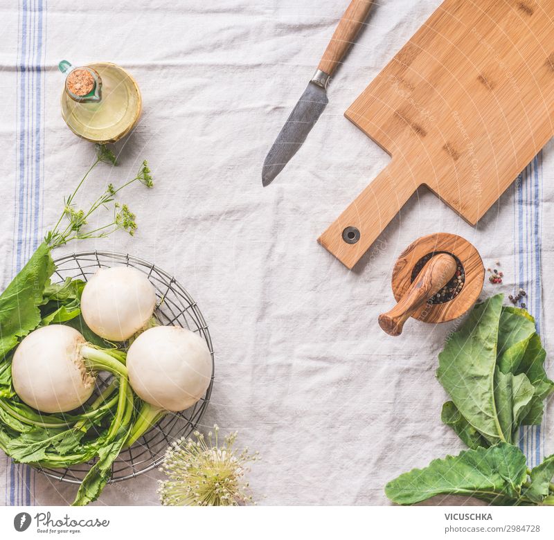 Food background with raw young turnip  with greens on light kitchen table with cutting board and knife, top view. Healthy vegetarian eating and cooking concept. Copy space for your design