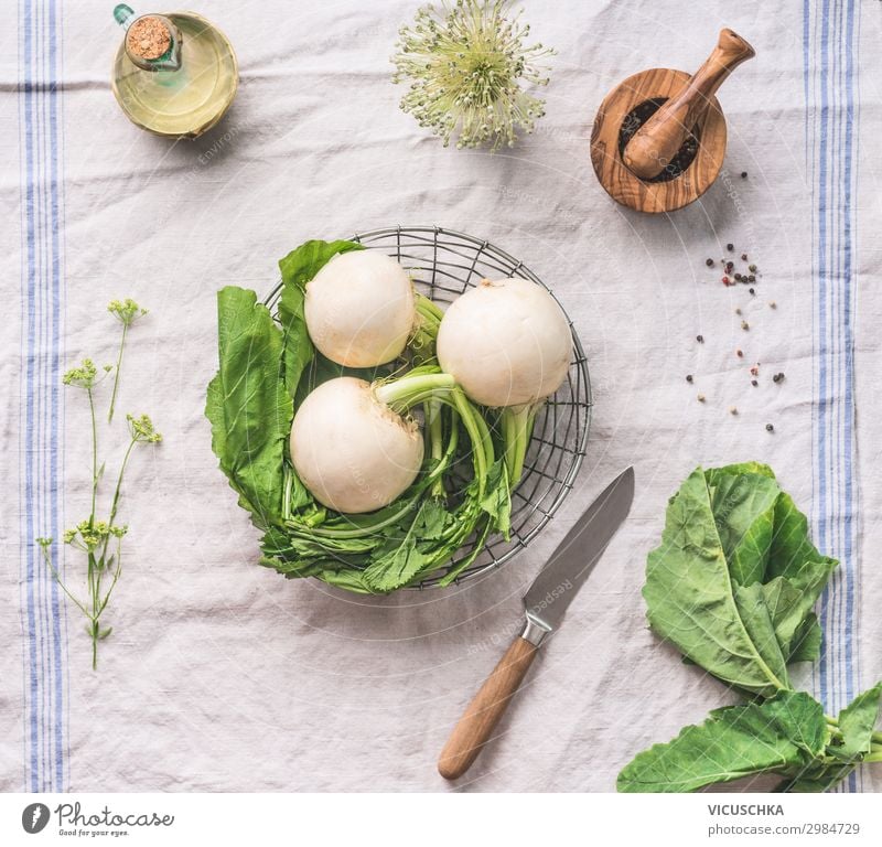 Raw young turnip  with greens on light kitchen table with knife, top view. Healthy vegetarian eating and cooking concept raw healthy green foods green colors