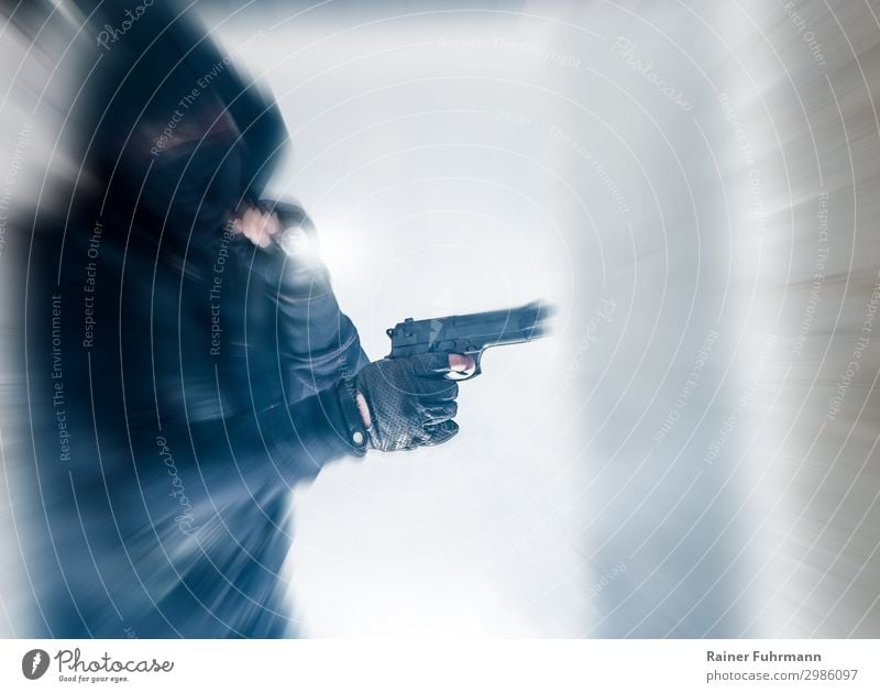 A hooded man in a mask is holding a gun Robbery robber criminal burglars Weapon Handgun Break-in Shoot Hooded (clothing) Mask blurred disguised Thief