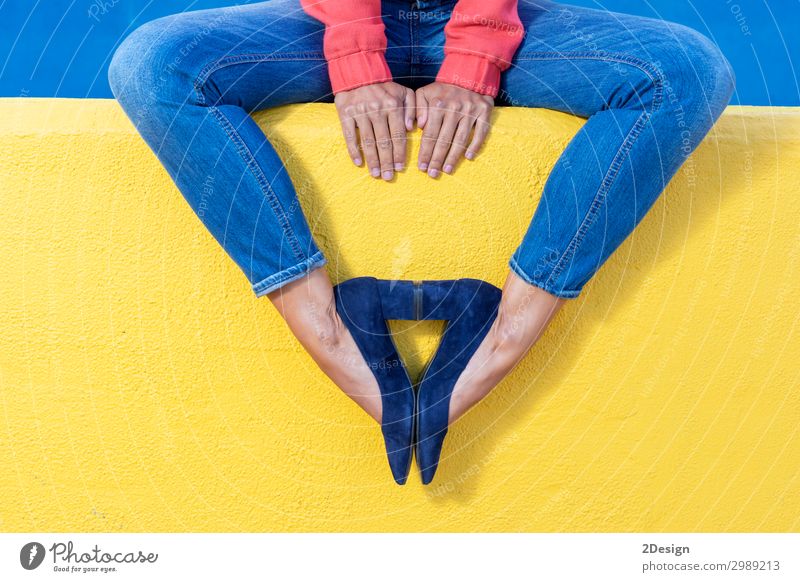 Woman in jeans sitting on yellow wall making pattern with heels Lifestyle Style Beautiful Relaxation Summer Human being Adults Feet Warmth Fashion Jeans
