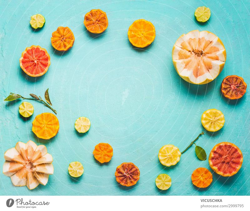 Frame of various colorful citrus fruits halves with green leaves on light blue background, top view. Copy space for your design. Flat lay. Healthy food ad lifestyle concept. Source of vitamin C