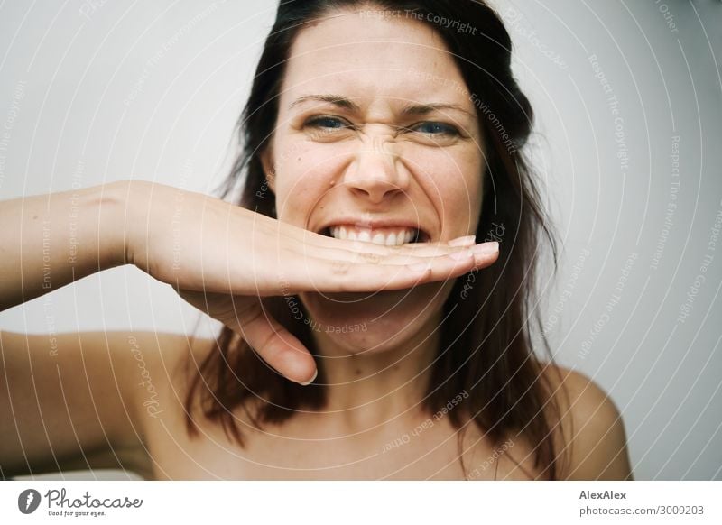 Close portrait of a young woman biting her hand in front of a white wall Lifestyle Joy already Young woman Youth (Young adults) Face by hand 18 - 30 years