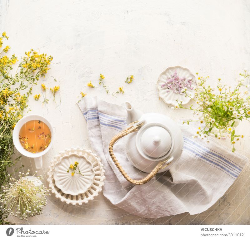 Herbal tea setting with fresh medical herbs , teapot and cup of tea. Saint-John's-wort herbs and flowers on white table background, top view. Herbal medicine. Natural dietary supplement