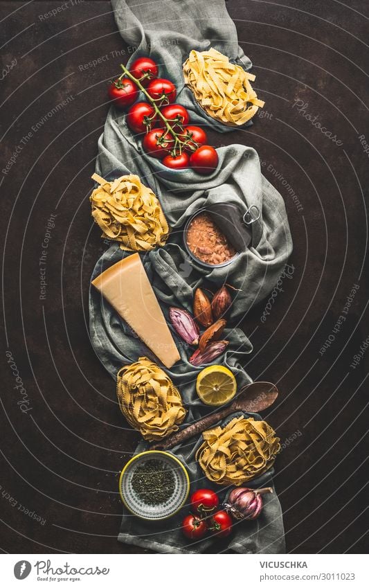 Tuna pasta cooking ingredients on dark rustic background, top view. Grocery products of Italian cuisine. Italian food. Caned tuna. Vertical. Flat lay grocery