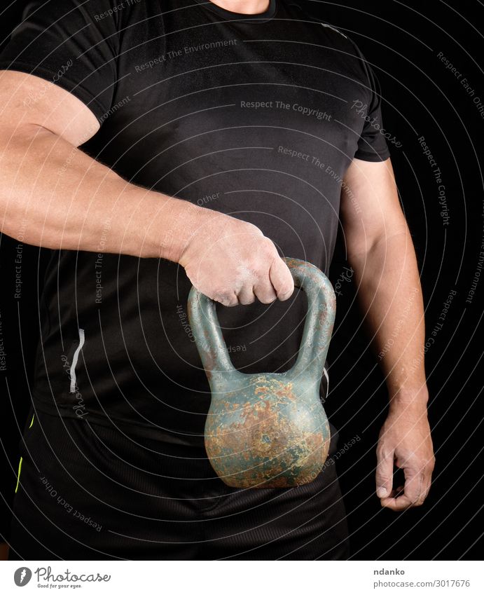 strong athlete in black clothes holding an iron kettlebell Lifestyle Sports Human being Man Adults Arm Hand Fingers 1 30 - 45 years Fitness Stand Athletic Dark