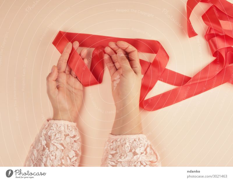 two female hands and red silk ribbon - a Royalty Free Stock Photo