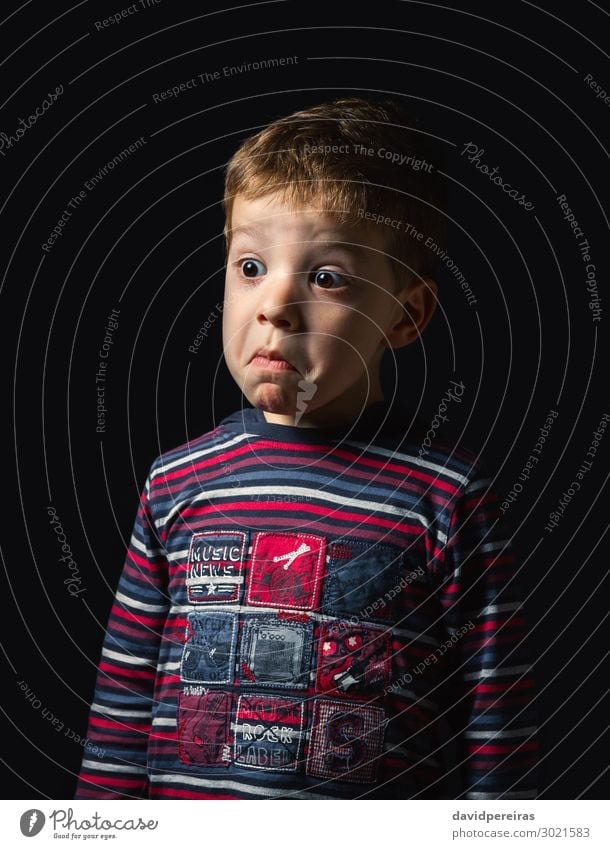 Confused boy with doubt face over black background Face Child Human being Boy (child) Man Adults Infancy Shirt Stripe Think Stand Authentic Dark Small Cute Red