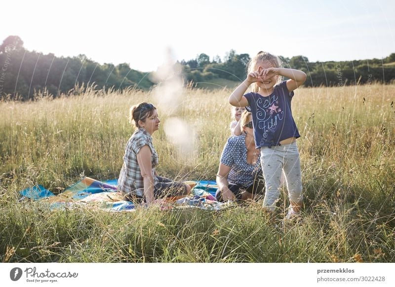 Little cute adorable girl enjoying a cool water sprayed by her mother  during hot summer day in backyard. Candid people, real moments, authentic  situations - a Royalty Free Stock Photo from Photocase