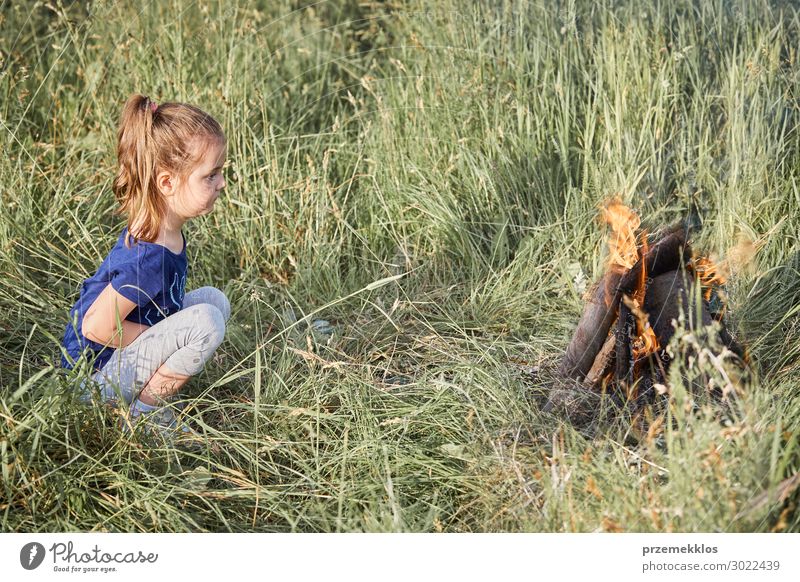 Little girl looking at campfire sitting in a grass Lifestyle Joy Happy Relaxation Vacation & Travel Summer Summer vacation Child Human being Girl Woman Adults 1